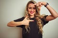 Young beautiful woman wearing black t-shirt standing over white isolated background smiling making frame with hands and fingers Royalty Free Stock Photo