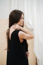 Young beautiful woman wearing a black V-neck dress. View from the side. Royalty Free Stock Photo