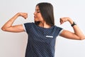Young beautiful woman wearing blue casual t-shirt standing over isolated white background showing arms muscles smiling proud Royalty Free Stock Photo
