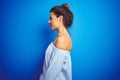 Young beautiful woman wearing bun hairstyle over blue isolated background looking to side, relax profile pose with natural face Royalty Free Stock Photo