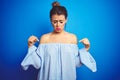 Young beautiful woman wearing bun hairstyle over blue isolated background Pointing down looking sad and upset, indicating Royalty Free Stock Photo