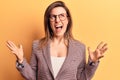 Young beautiful woman wearing business clothes and glasses crazy and mad shouting and yelling with aggressive expression and arms Royalty Free Stock Photo