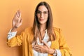 Young beautiful woman wearing business style and glasses swearing with hand on chest and open palm, making a loyalty promise oath