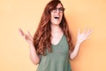 Young beautiful woman wearing casual clothes and glasses crazy and mad shouting and yelling with aggressive expression and arms Royalty Free Stock Photo