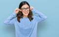 Young beautiful woman wearing casual clothes and glasses smiling pulling ears with fingers, funny gesture Royalty Free Stock Photo