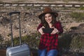 young beautiful woman wearing casual clothes, walking by the railway with suitcase and mobile phone and smiling. Outdoors Royalty Free Stock Photo