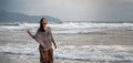 Woman wearing casual clothing enjoying sea storm and water waves of the sea on the beach Royalty Free Stock Photo