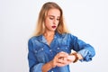 Young beautiful woman wearing casual denim shirt standing over isolated white background Checking the time on wrist watch, relaxed Royalty Free Stock Photo