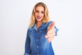 Young beautiful woman wearing casual denim shirt standing over isolated white background smiling friendly offering handshake as Royalty Free Stock Photo