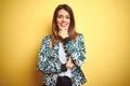 Young beautiful woman wearing casual jacket over yellow isolated background looking confident at the camera smiling with crossed Royalty Free Stock Photo