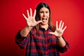 Young beautiful woman wearing casual shirt over red background afraid and terrified with fear expression stop gesture with hands, Royalty Free Stock Photo