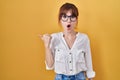 Young beautiful woman wearing casual shirt over yellow background surprised pointing with hand finger to the side, open mouth Royalty Free Stock Photo