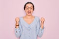 Young beautiful woman wearing casual striped shirt and glasses over pink background very happy and excited doing winner gesture Royalty Free Stock Photo