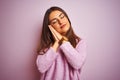 Young beautiful woman wearing casual sweater standing over isolated pink background sleeping tired dreaming and posing with hands Royalty Free Stock Photo