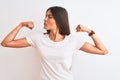 Young beautiful woman wearing casual t-shirt standing over isolated white background showing arms muscles smiling proud Royalty Free Stock Photo