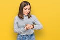 Young beautiful woman wearing casual turtleneck sweater checking the time on wrist watch, relaxed and confident Royalty Free Stock Photo