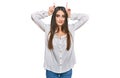 Young beautiful woman wearing casual white shirt doing funny gesture with finger over head as bull horns Royalty Free Stock Photo