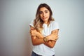 Young beautiful woman wearing casual white t-shirt over  background shaking and freezing for winter cold with sad and Royalty Free Stock Photo