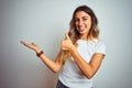 Young beautiful woman wearing casual white t-shirt over isolated background Showing palm hand and doing ok gesture with thumbs up, Royalty Free Stock Photo