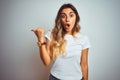 Young beautiful woman wearing casual white t-shirt over isolated background Surprised pointing with hand finger to the side, open Royalty Free Stock Photo