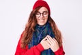 Young beautiful woman wearing casual winter scarf and glasses smiling with hands on chest with closed eyes and grateful gesture on Royalty Free Stock Photo