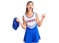 Young beautiful woman wearing cheerleader uniform surprised pointing with finger to the side, open mouth amazed expression Royalty Free Stock Photo