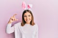 Young beautiful woman wearing cute easter bunny ears smiling and confident gesturing with hand doing small size sign with fingers Royalty Free Stock Photo