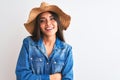 Young beautiful woman wearing denim shirt and hat standing over isolated white background happy face smiling with crossed arms Royalty Free Stock Photo