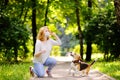 Young beautiful woman wearing disposable medical face mask playing with Beagle dog in the park during coronavirus outbreak.