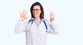 Young beautiful woman wearing doctor stethoscope and glasses showing and pointing up with fingers number nine while smiling Royalty Free Stock Photo