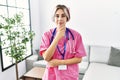 Young beautiful woman wearing doctor uniform and stethoscope looking confident at the camera with smile with crossed arms and hand Royalty Free Stock Photo