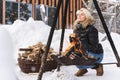 Beautiful woman warming up by the fire pit during cold winter day Royalty Free Stock Photo