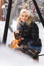Beautiful woman warming up by the fire pit during cold winter day Royalty Free Stock Photo
