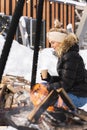 Beautiful woman warming up by the fire pit during cold winter day Royalty Free Stock Photo