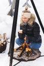 Beautiful woman warming up by the fire pit during cold winter day Royalty Free Stock Photo