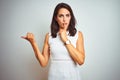 Young beautiful woman wearing dress standing over white isolated background asking to be quiet with finger on lips pointing with Royalty Free Stock Photo