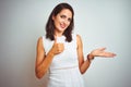 Young beautiful woman wearing dress standing over white isolated background Showing palm hand and doing ok gesture with thumbs up, Royalty Free Stock Photo