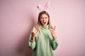Young beautiful woman wearing easter rabbit ears standing over isolated pink background shouting with crazy expression doing rock Royalty Free Stock Photo
