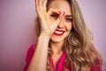 Young beautiful woman wearing elegant shirt standing over pink isolated background with happy face smiling doing ok sign with hand Royalty Free Stock Photo