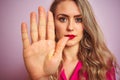 Young beautiful woman wearing elegant shirt standing over pink isolated background with open hand doing stop sign with serious and Royalty Free Stock Photo