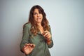 Young beautiful woman wearing green shirt standing over grey isolated background disgusted expression, displeased and fearful Royalty Free Stock Photo