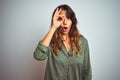 Young beautiful woman wearing green shirt standing over grey isolated background doing ok gesture shocked with surprised face, eye Royalty Free Stock Photo