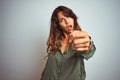 Young beautiful woman wearing green shirt standing over grey isolated background pointing displeased and frustrated to the camera, Royalty Free Stock Photo