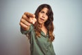 Young beautiful woman wearing green shirt standing over grey isolated background pointing displeased and frustrated to the camera, Royalty Free Stock Photo