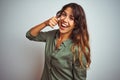 Young beautiful woman wearing green shirt standing over grey isolated background smiling doing phone gesture with hand and fingers Royalty Free Stock Photo