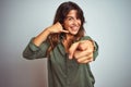 Young beautiful woman wearing green shirt standing over grey isolated background smiling doing talking on the telephone gesture Royalty Free Stock Photo