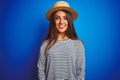 Young beautiful woman wearing navy striped t-shirt and hat over isolated blue background with a happy and cool smile on face Royalty Free Stock Photo