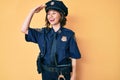 Young beautiful woman wearing police uniform very happy and smiling looking far away with hand over head Royalty Free Stock Photo