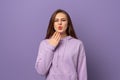 Young beautiful woman wearing purple hoodie, standing over purple background covering mouth with hand, shocked and afraid for Royalty Free Stock Photo