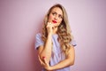 Young beautiful woman wearing purple t-shirt standing over pink isolated background with hand on chin thinking about question, Royalty Free Stock Photo